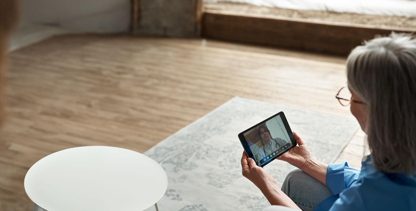 a woman using a tablet for a telehealth appointment, connected by Viasat satellite internet